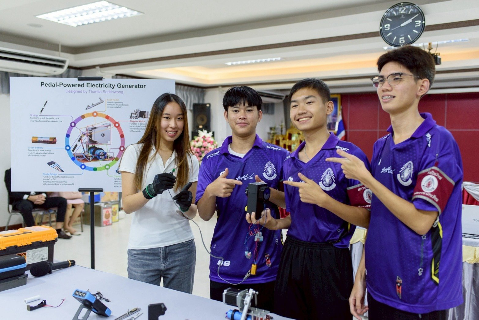 Winnie and students holding parts of the pedal-powered generator